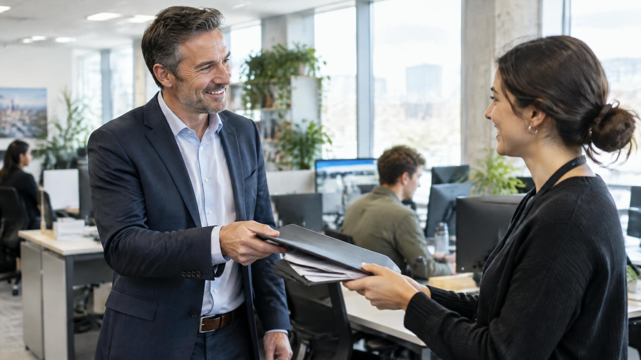 Manager handing over a folder of documents to a colleague